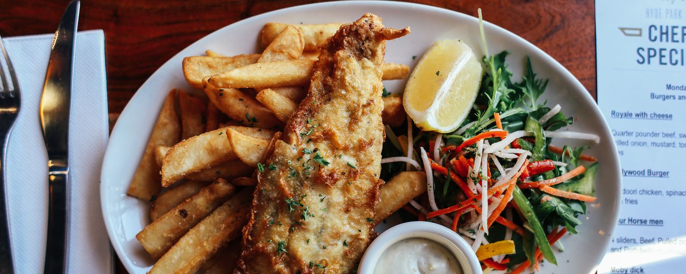 A plate of battered fish and chips with salad on a restaurant table