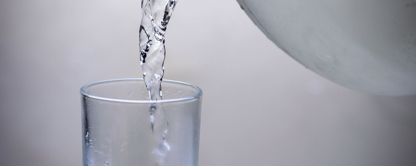 Water being poured from a jug into a clear drinking glass