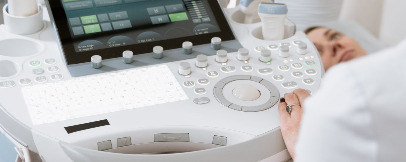 An ultrasound machine console beside a patient lying on an examination bed