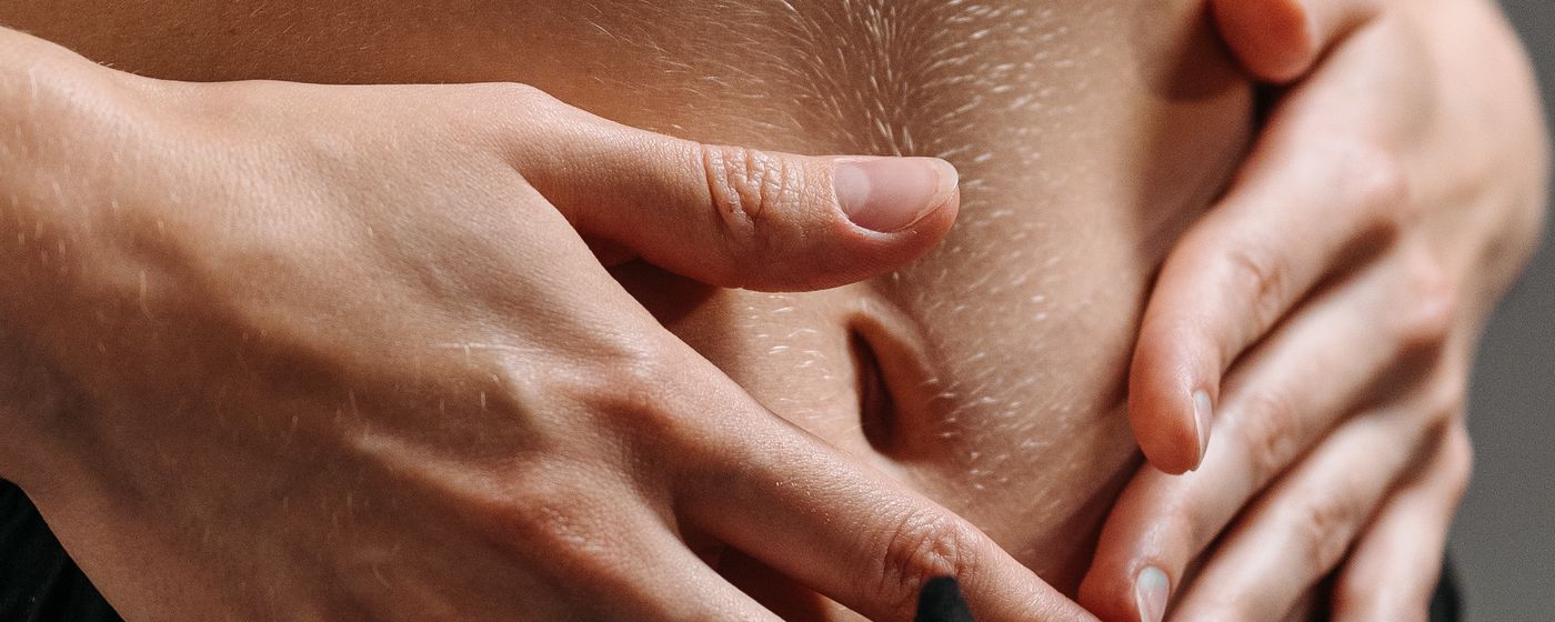 A person resting both hands on their midriff