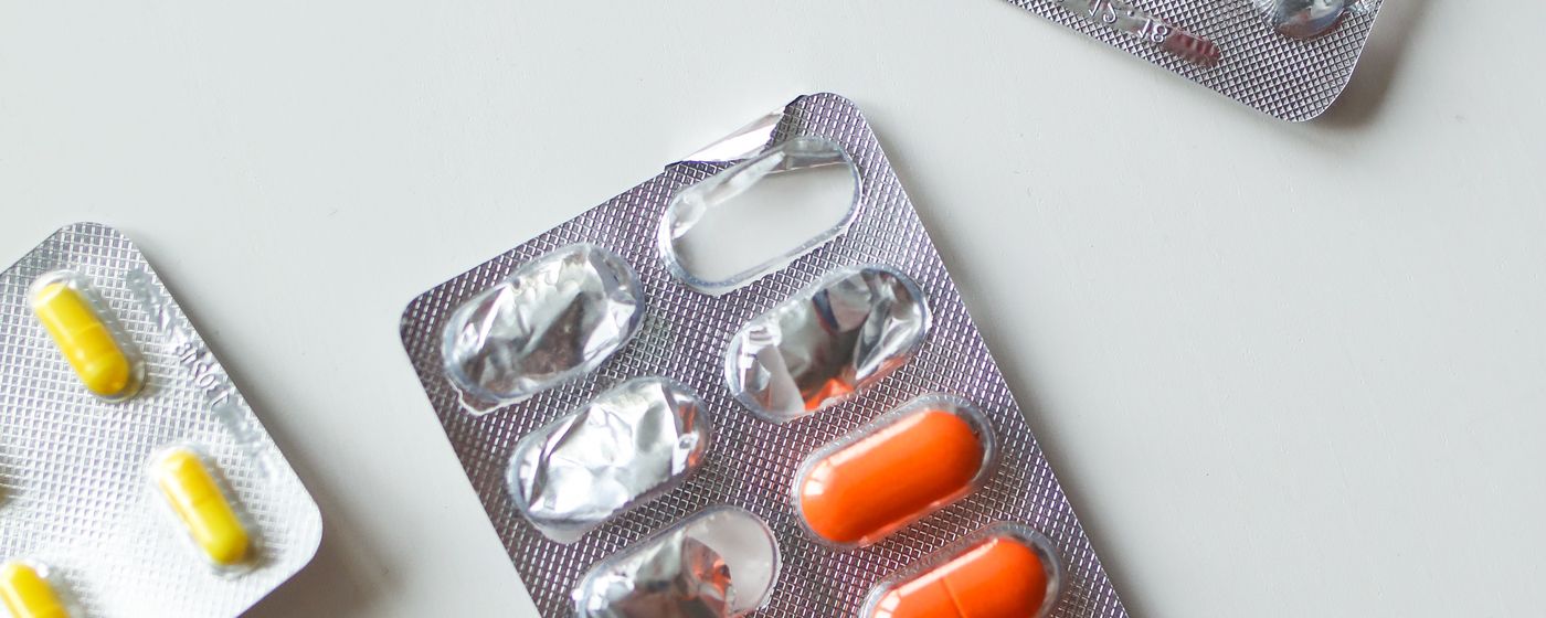Blister packs of coloured capsules and tablets on a plain white surface