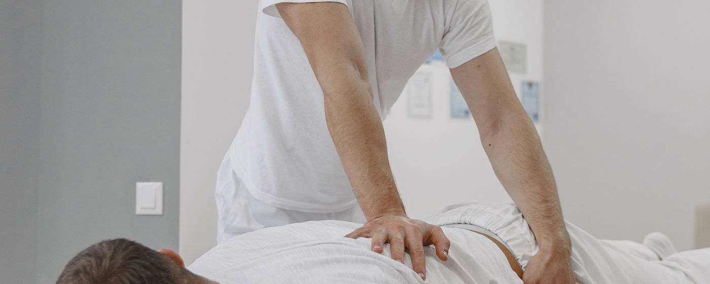 A therapist working on the back of a person lying face down on a treatment table