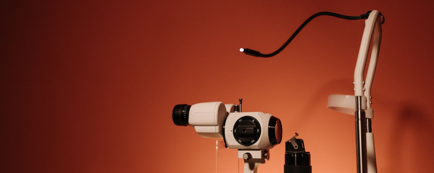 A slit lamp eye examination instrument standing in a darkened clinic room