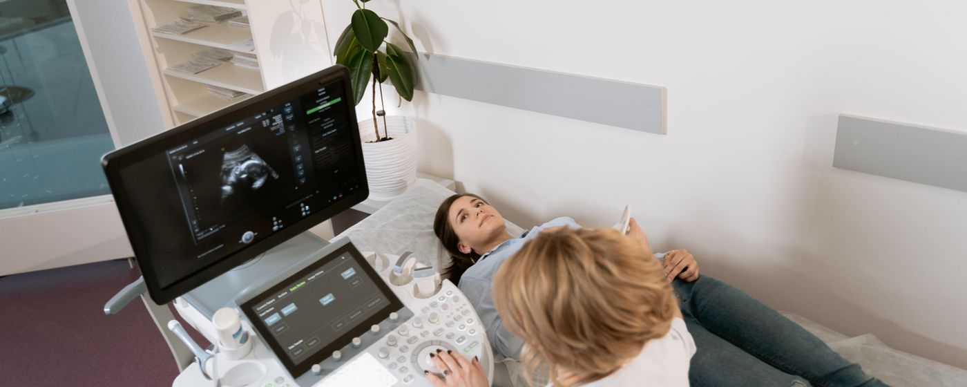 A sonographer performing an ultrasound scan on a patient lying on an examination couch