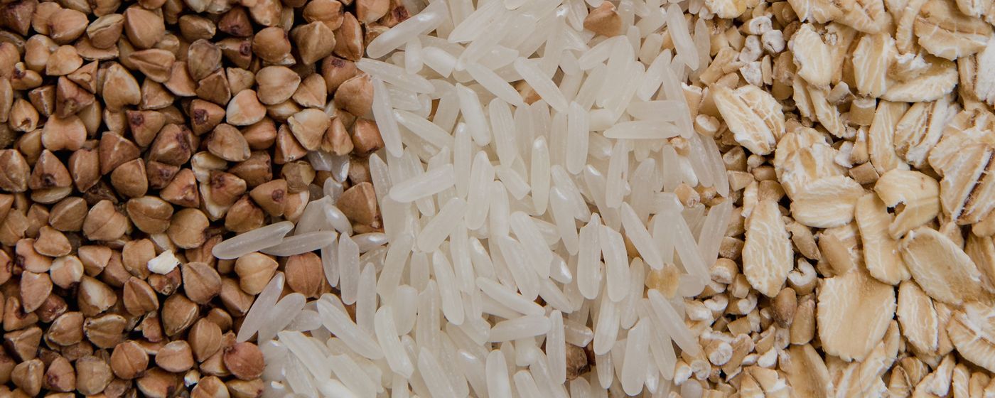 Buckwheat groats, white rice and rolled oats side by side filling the frame