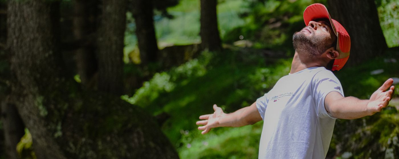 A man with open arms breathing deeply in a green forest