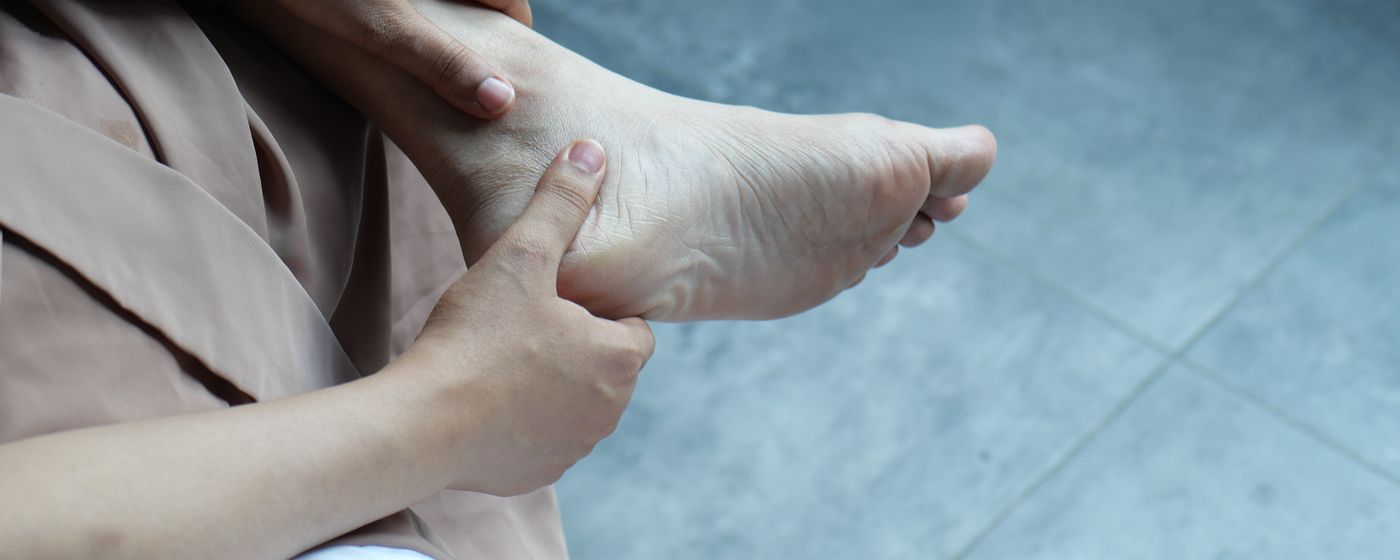 A person sitting down and holding a painful bare foot