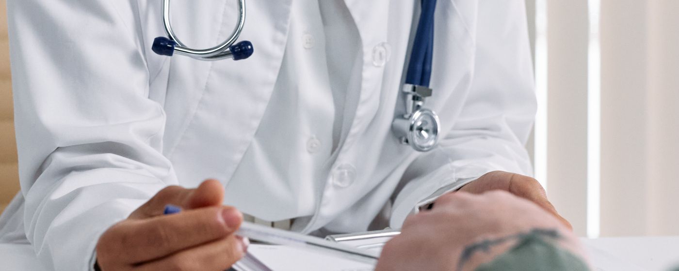 A doctor reviews documents with a patient at a clinic table
