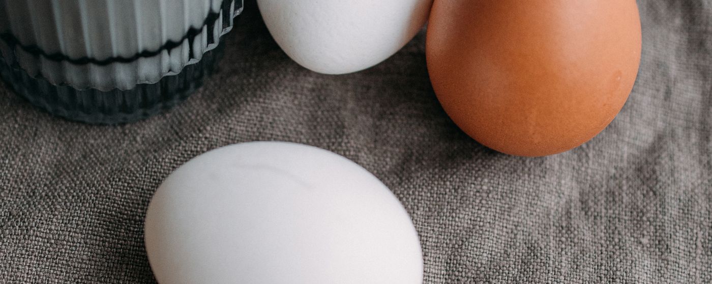 Brown and white eggs beside a glass of milk on a linen cloth