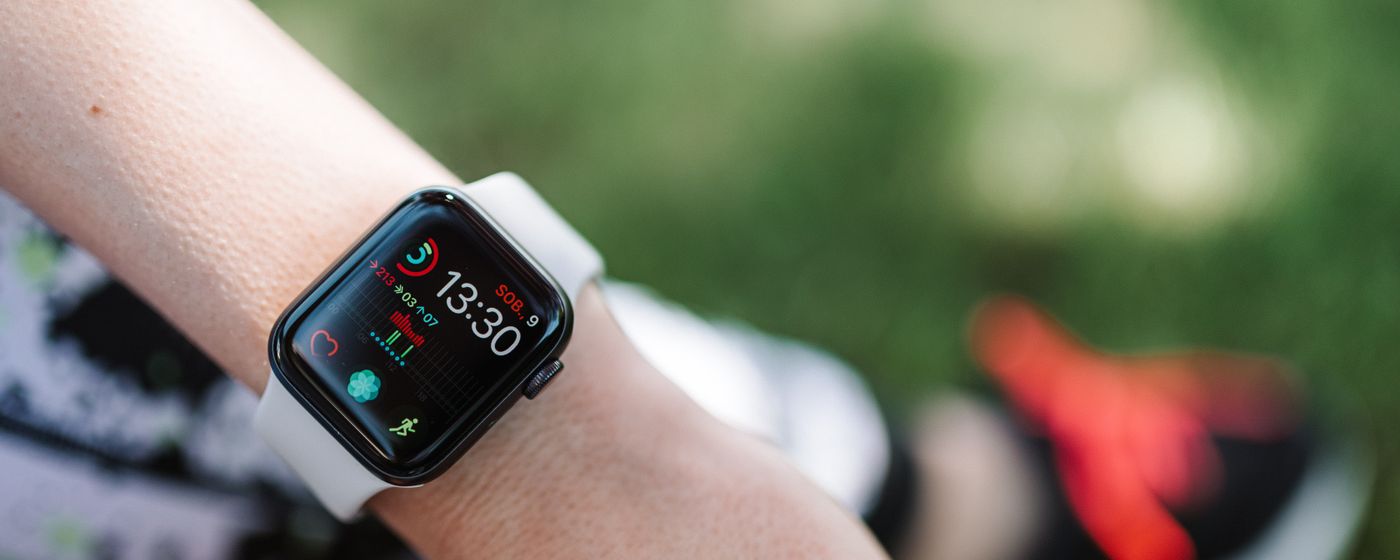A smartwatch on a wrist showing health and heart metrics outdoors