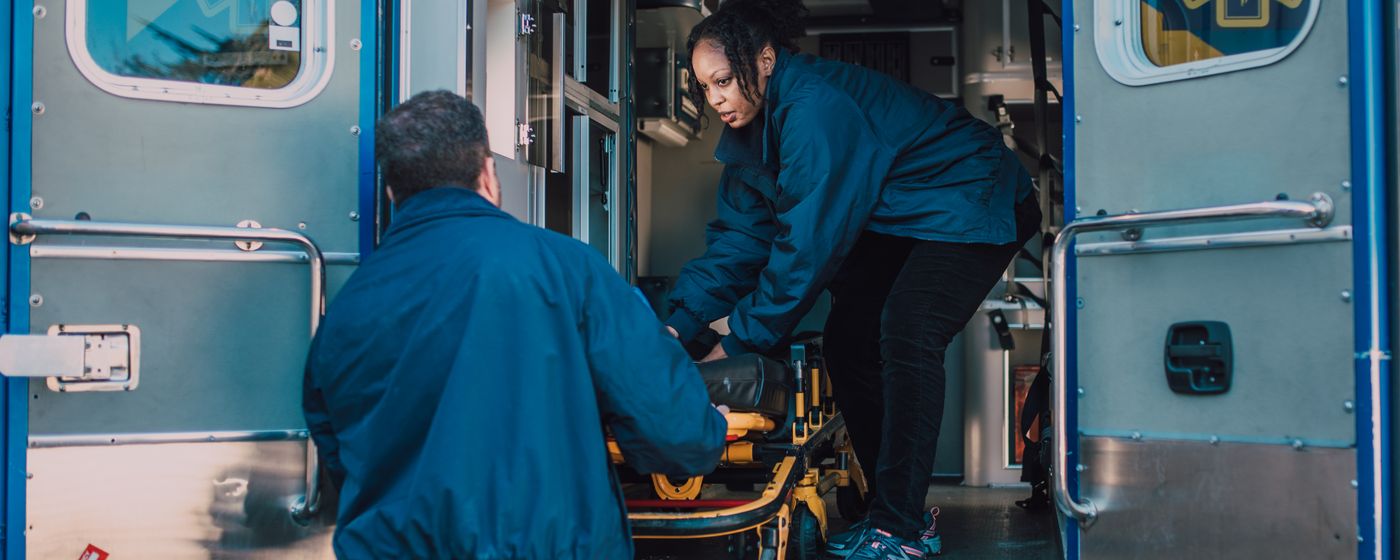 Two paramedics loading a stretcher into an ambulance