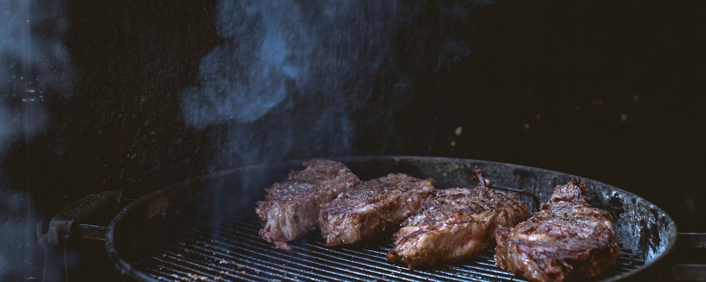 Red meat cooking over an open charcoal grill