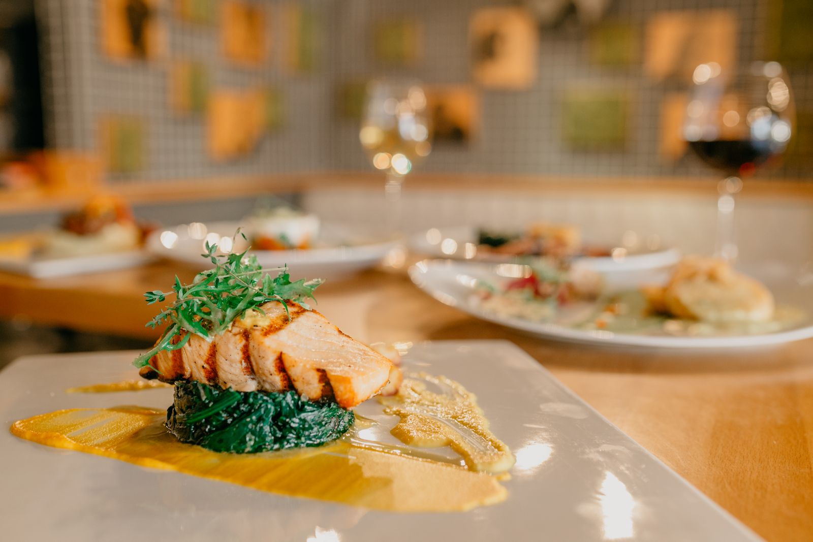 A grilled salmon fillet served with spinach on a white plate at a restaurant table