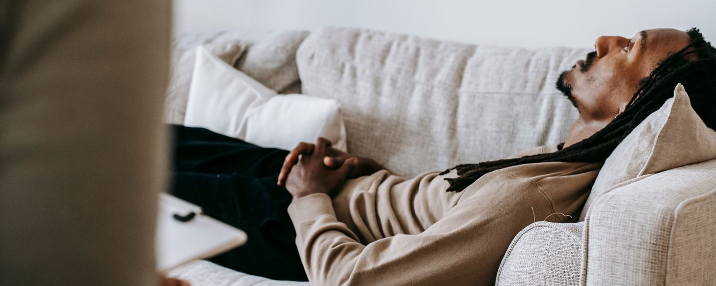 A man lying on a couch talking with a counselor during a therapy session