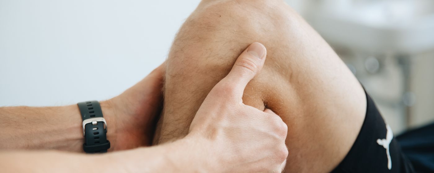 A physical therapist's hands examining a patient's knee