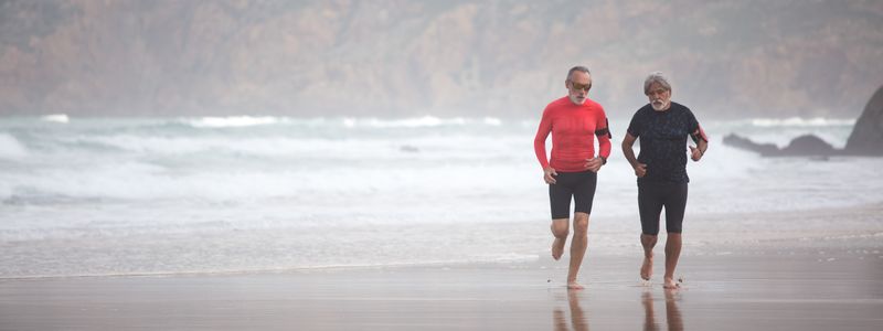 Two men walking together on a beach in the morning