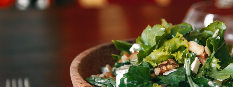 A green salad with walnuts and crumbled feta in a wooden bowl