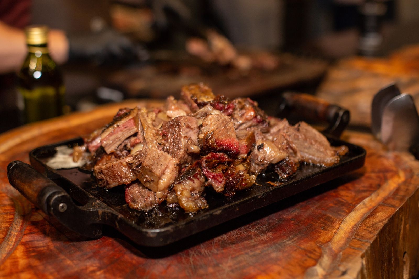 Grilled beef served on a cast iron plate at a wooden table