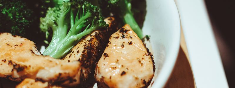 A plate of sliced cooked chicken breast served with broccoli