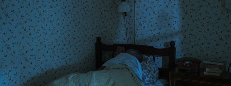 A person asleep in bed in a dimly lit bedroom at night