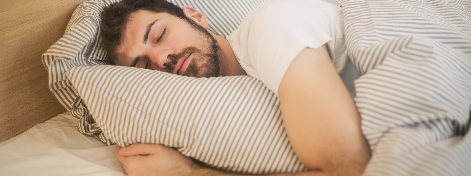 A person sleeping soundly in bed under a striped duvet