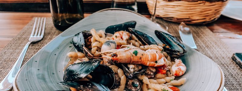 A plate of shellfish including mussels and shrimp with pasta