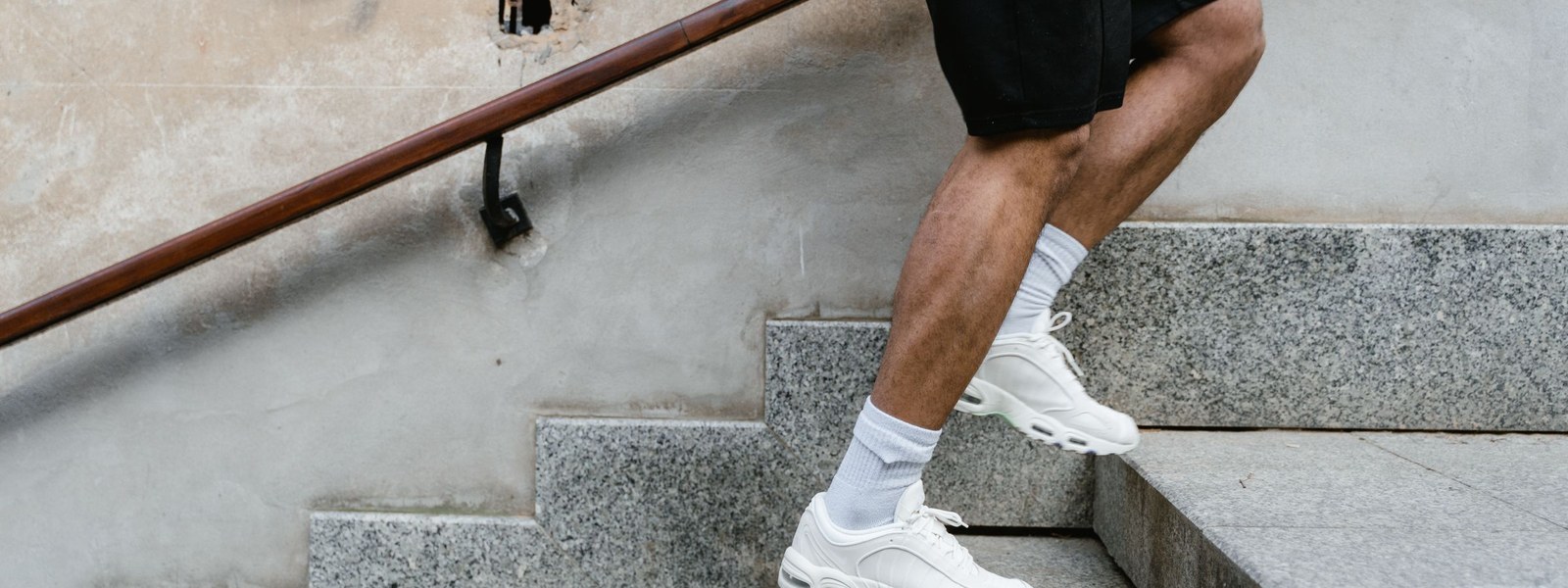 Close view of a person's legs stepping up a stone staircase in running shoes