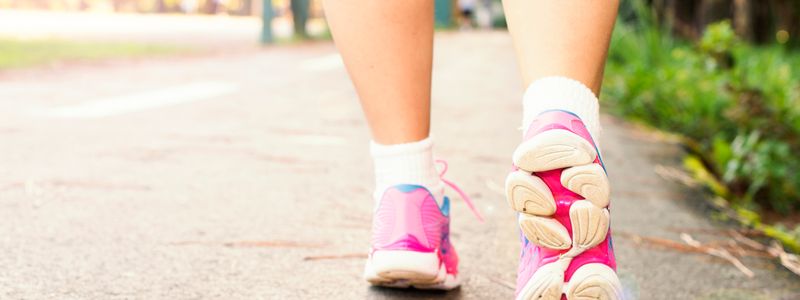 Close-up of a person's feet in running shoes taking a heel-to-toe stride on a paved path