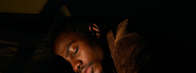 A man asleep on his side in a dimly lit bedroom