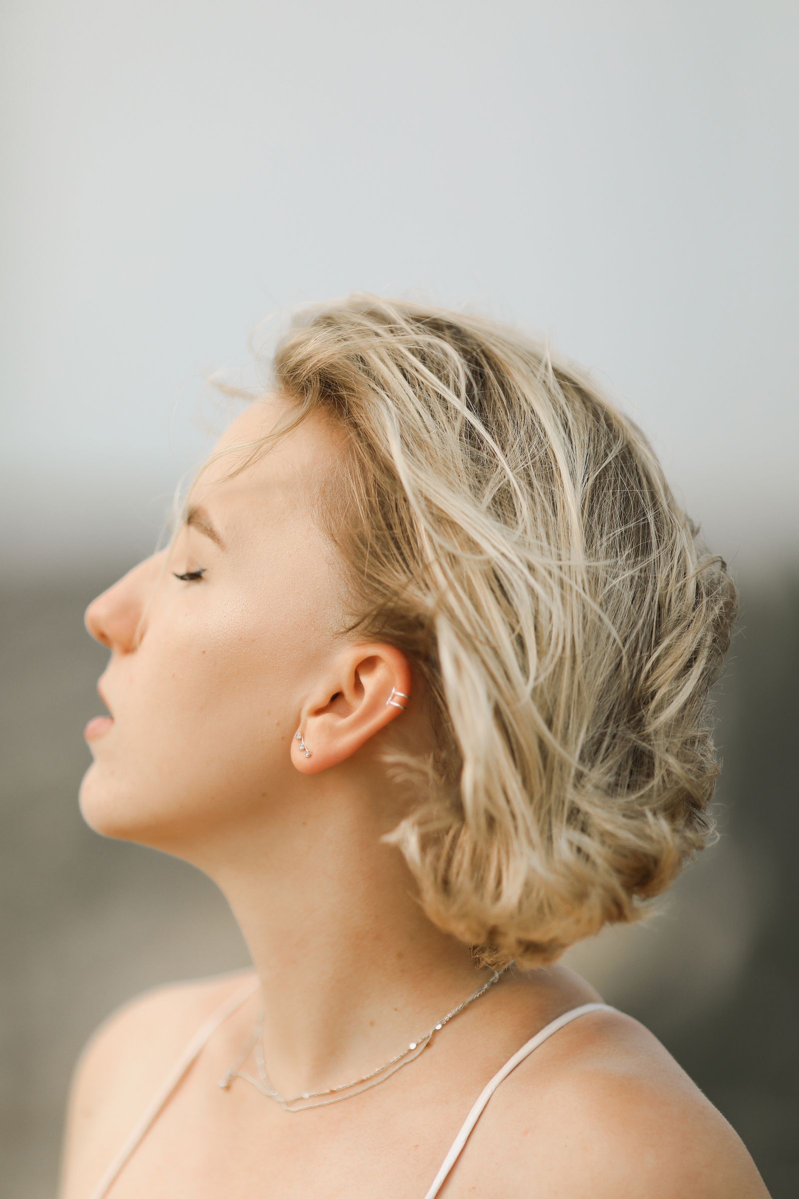 A woman with her eyes closed taking a slow breath in soft daylight
