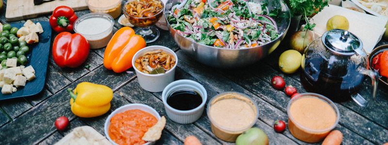 A spread of Mediterranean vegetables, salad and dips on a wooden table