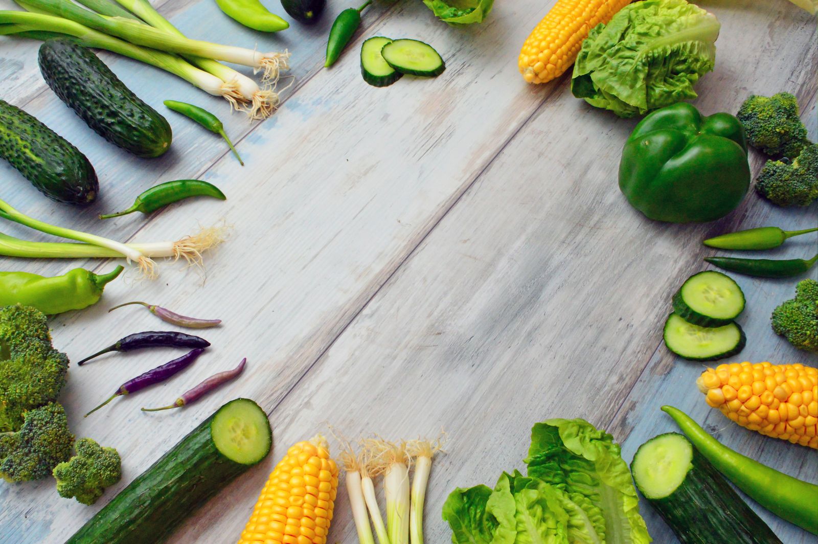 Fresh green vegetables including broccoli, cucumber and corn on a wooden table