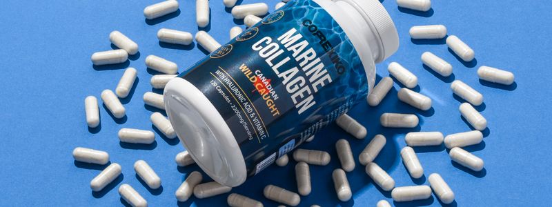 A bottle of collagen supplement capsules spilled across a blue background