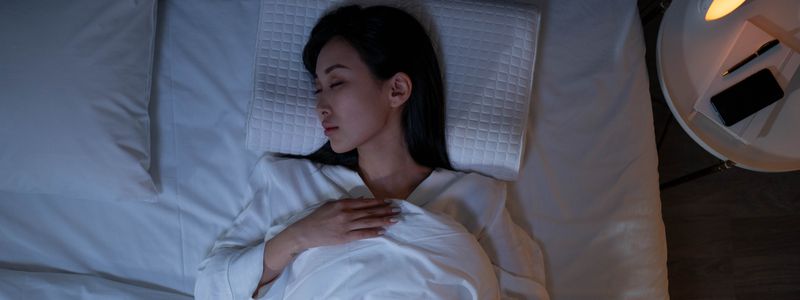 A woman lying awake in a dimly lit bedroom at night