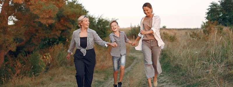 A mother, a young boy and a young woman walking together along a countryside path at dusk
