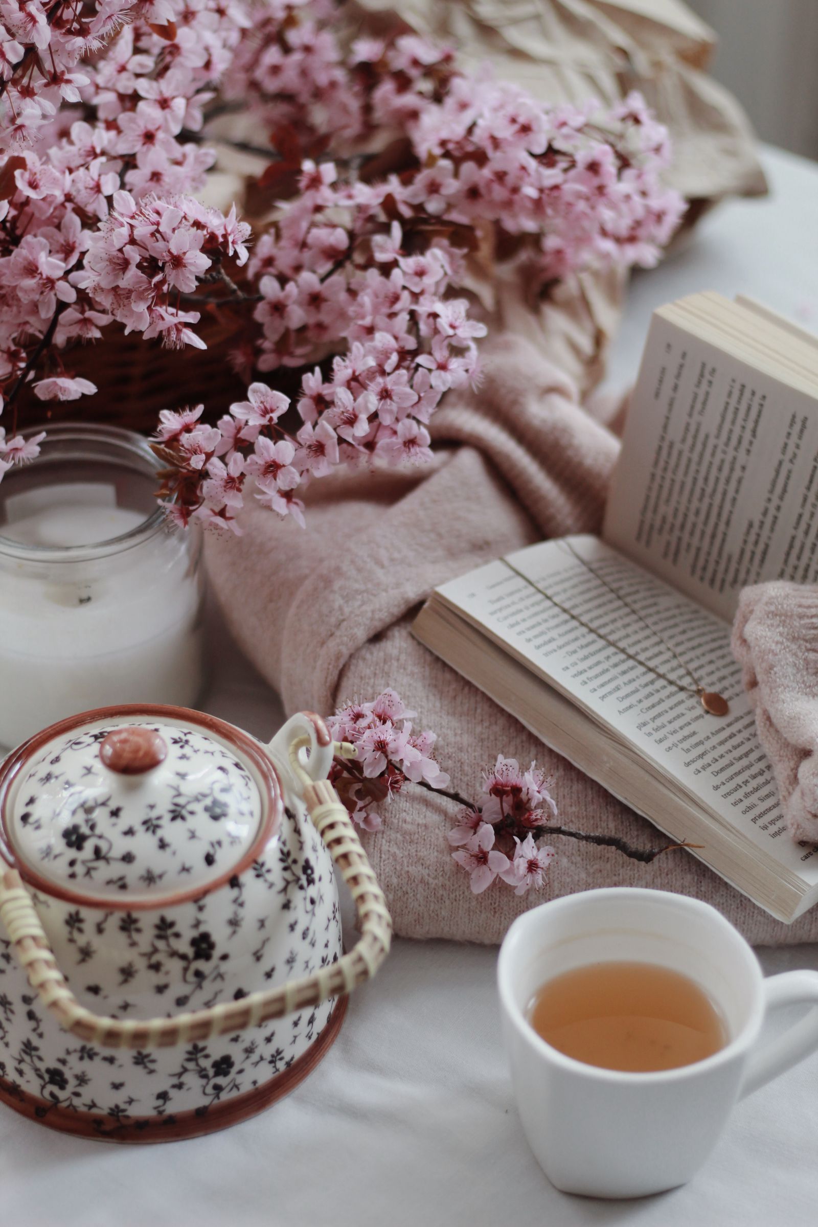 A warm cup of herbal tea beside an open book and soft blanket in calm light