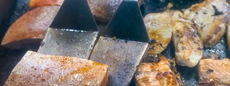 Fillets of oily fish being cooked on a flat griddle