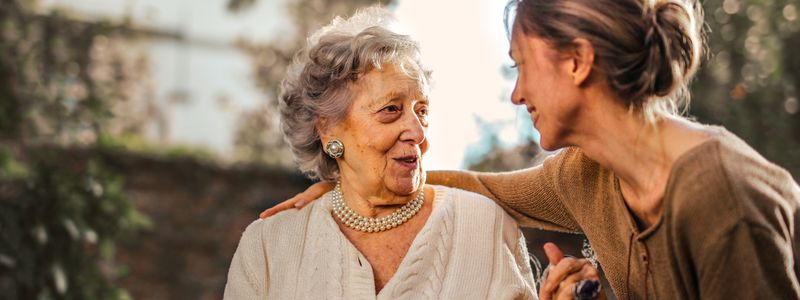 An older woman in warm conversation with a younger family member outdoors