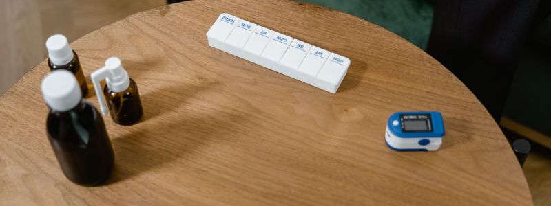 A weekly pill organizer and two amber medicine bottles on a round wooden table