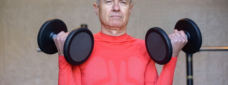 Older man curling a pair of dumbbells