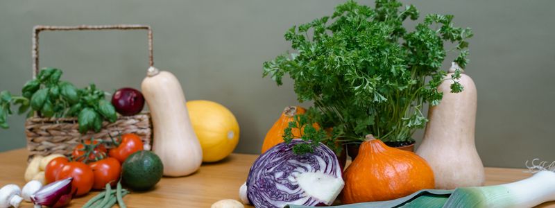 A basket and table full of fresh colorful vegetables and herbs