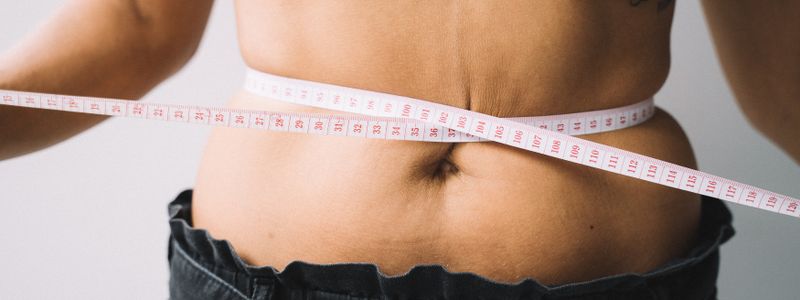 A tape measure wrapped around a person's midsection to check waist size