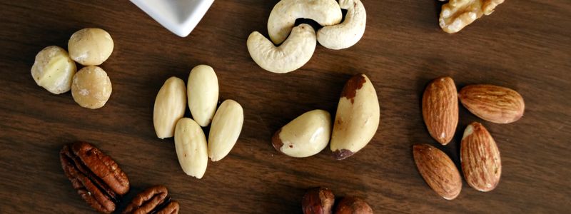 Assorted nuts including almonds, cashews, and walnuts on a wooden surface