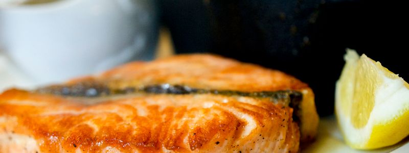 Pan-seared salmon fillet with a lemon wedge
