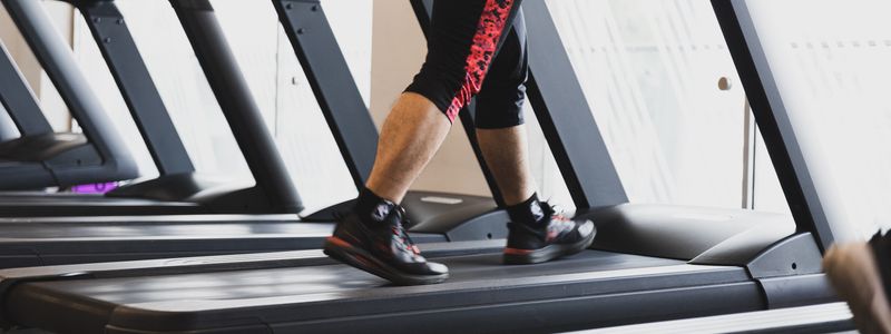 A person walking at a steady pace on a gym treadmill
