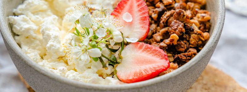 Bowl of cottage cheese with granola and sliced strawberries