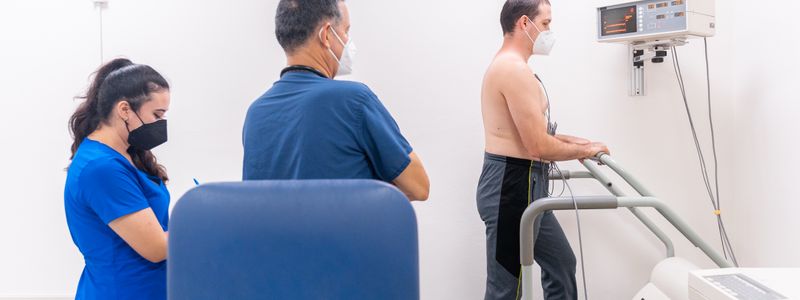 A clinician monitoring a patient walking on a treadmill during a cardiac stress test