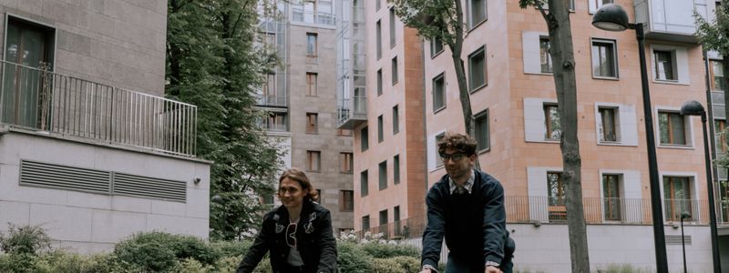 Two people riding bicycles along a tree lined city street
