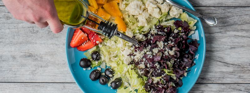 Olive oil being poured over a fresh salad