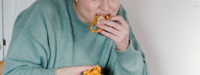 A person sitting and eating packaged snack food from their hand